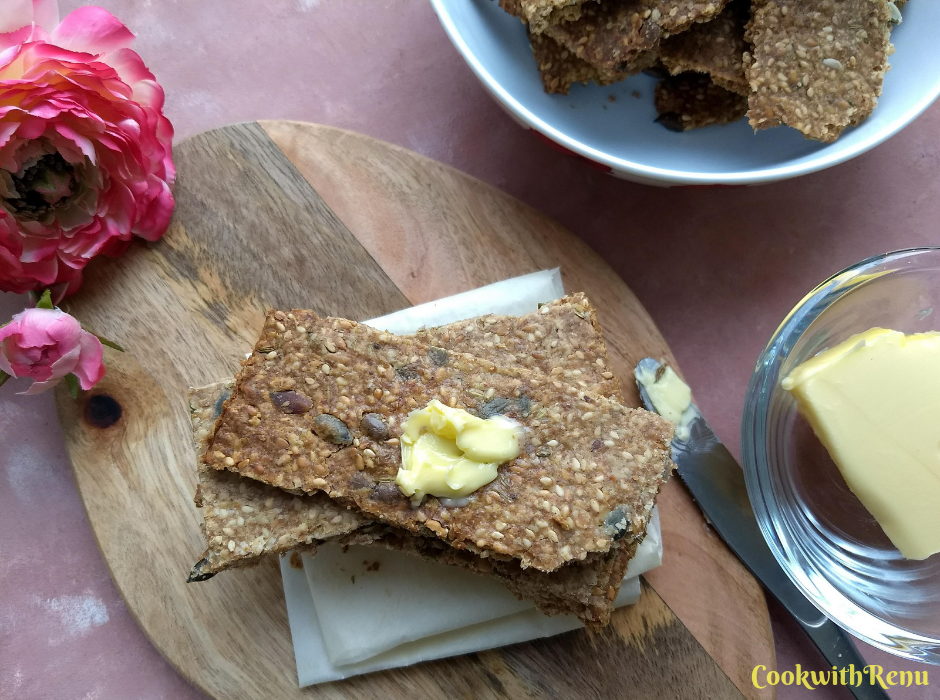 Top view of Knäckebröd - Swedish Multi-Seed Crispbread, served on a brown serving board with some butter spread on it