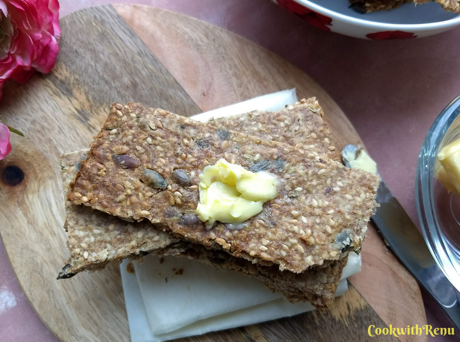 Knäckebröd - Swedish Multi-Seed Crispbread, served on a brown serving board with some butter spread on it