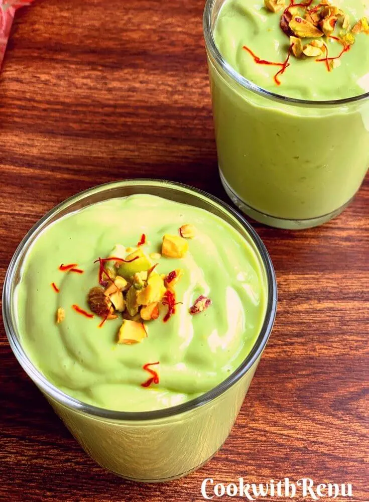 Closer look of thick, creamy and green colour, Indian Style Avocado Lassi, garnished with chopped pistachio and saffron strands