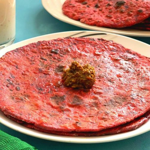 Closer look of the Red and Bright Beetroot Paratha, served with a dollop of a, chaar , dry vegetable and Buttermilk