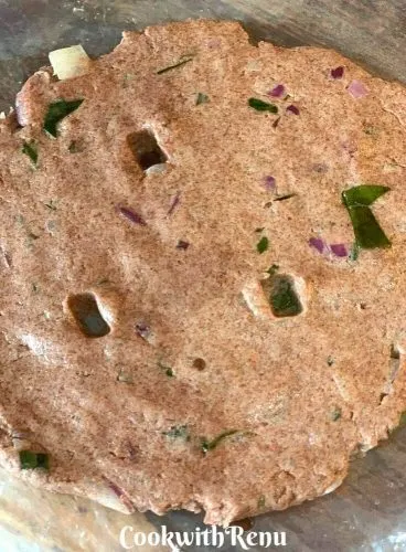 Ragi roti being patted on a polythene with holes poked into it