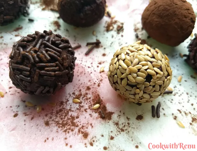 Close up look of Energy bites coated with chocolate vermicelli and sesame seeds, spread on a parchment paper