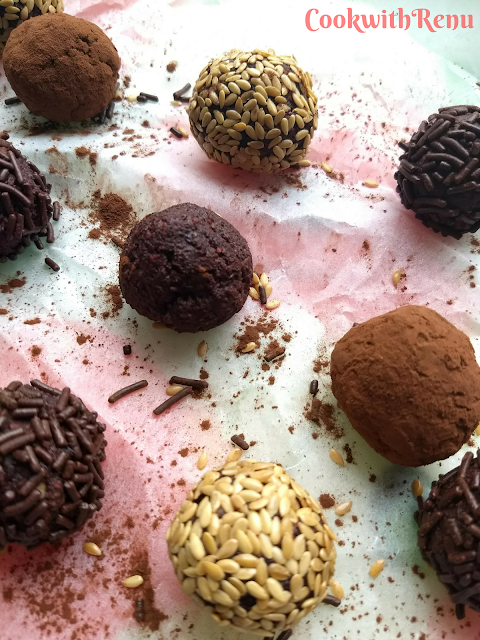 Beetroot and Dates Energy bites coated with chocolate vermicelli, cocoa powder and sesame seeds, spread on a parchment paper