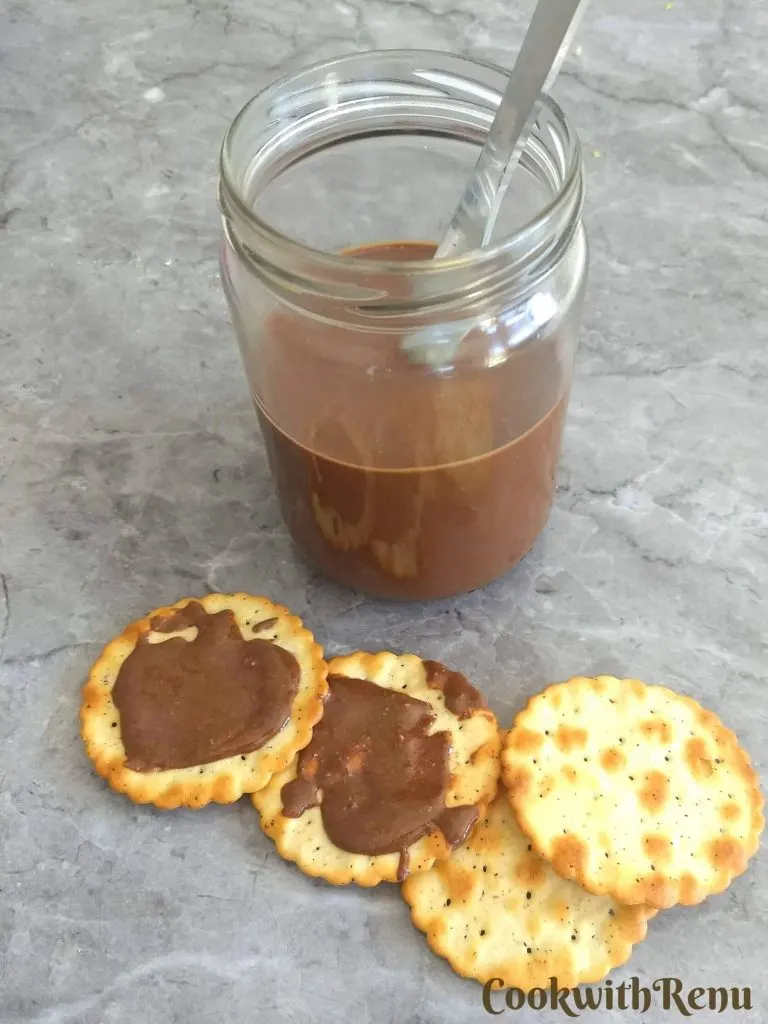 Crackers spread with Sugar-Free Hazelnut Chocolate Butter. A half bottle filled with chocolate butter