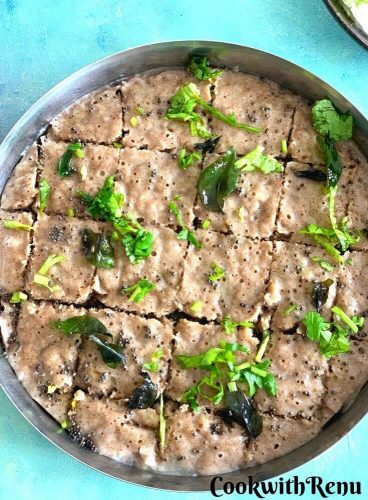 Steamed Farali Kuttu aur Singhare ke atte ka dhokla seen in a steel plate, with the tempering of mustard seeds, corainder and curry leaves.
