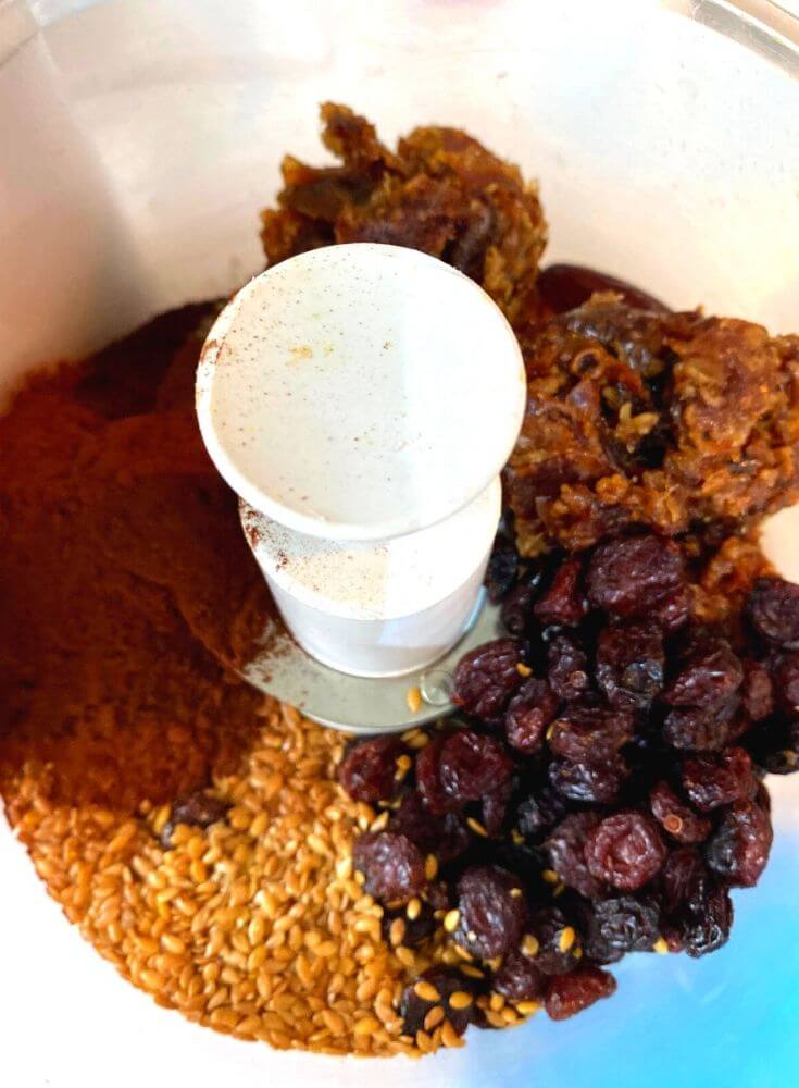 Adding the ingredients dates, cranberry, cocoa powder and flax seed in a food processor