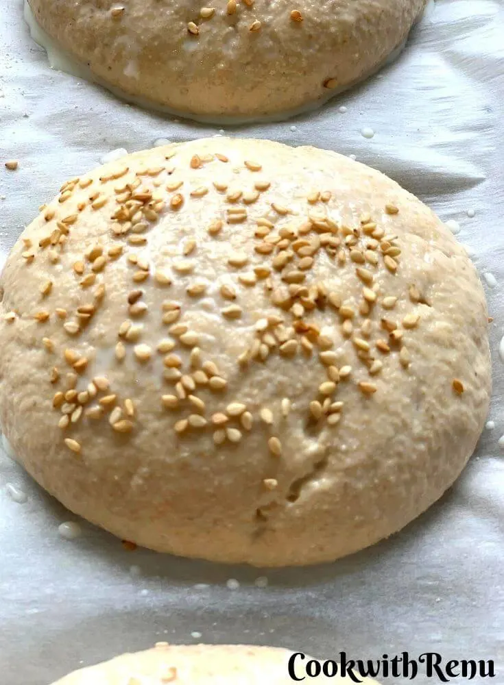 Close up look of a burger bun sprinkled with sesame seeds and ready to be baked