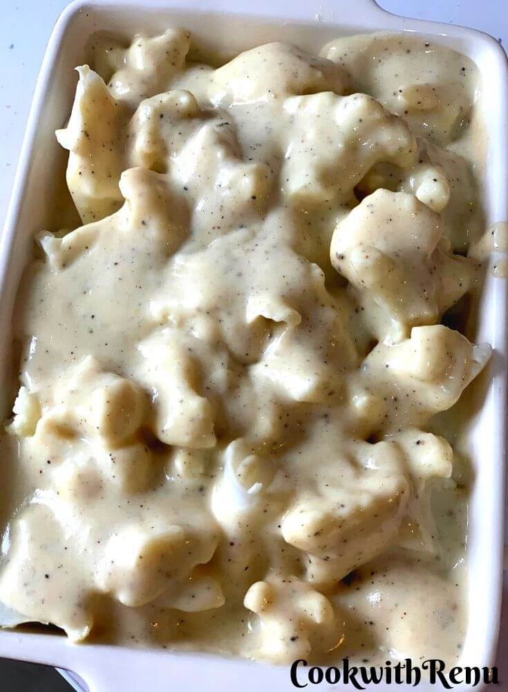 White sauce being poured on the cauliflower and ready to be baked