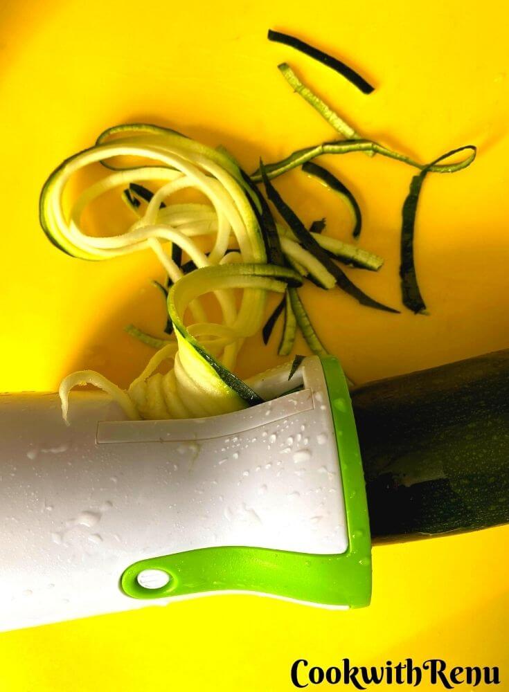 Zucchini is getting spiralized using a hand spiralizer