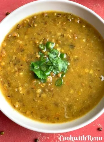 Close up look of Whole Green Moong Dal with a garnish of green chilly and coriander.
