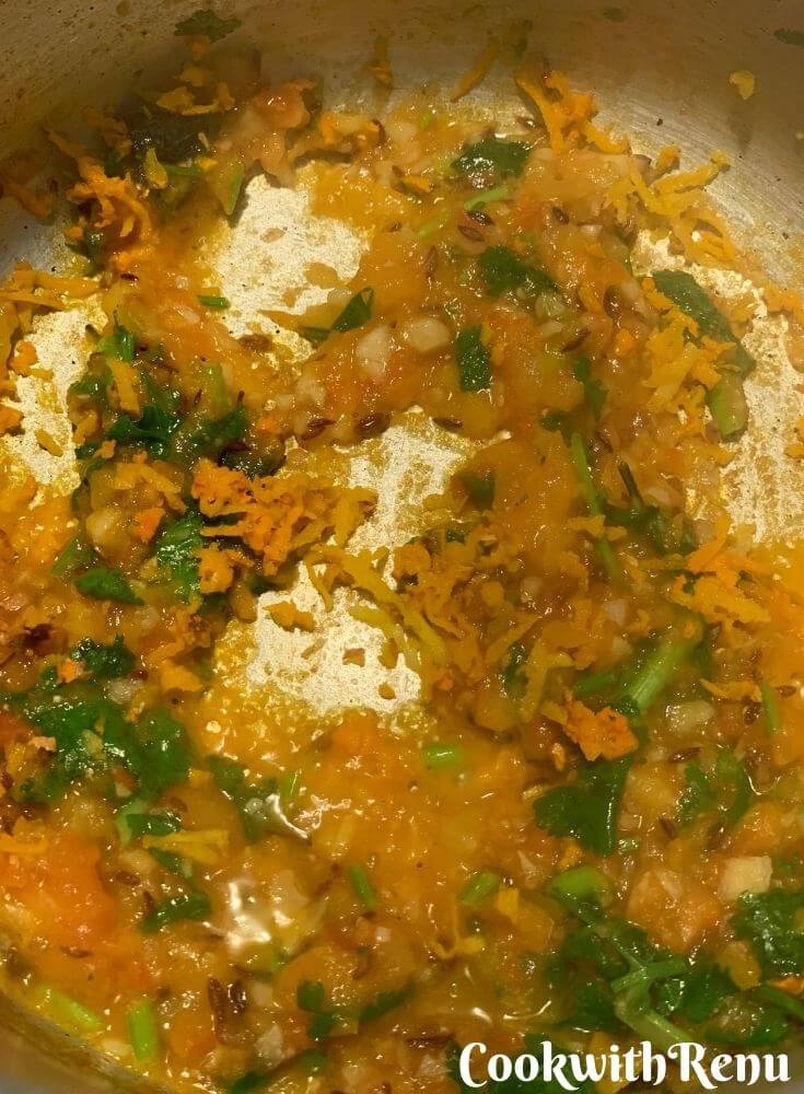 Addition of tomato puree, turmeric, and coriander to tadka