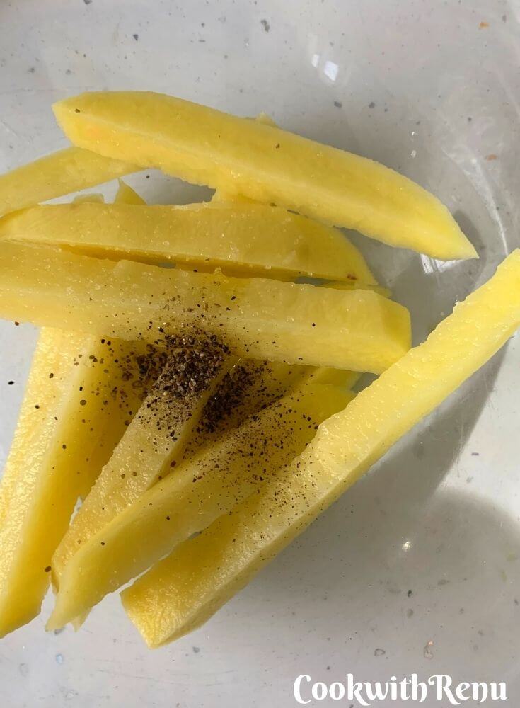 Potatoes being seasoned with salt and pepper