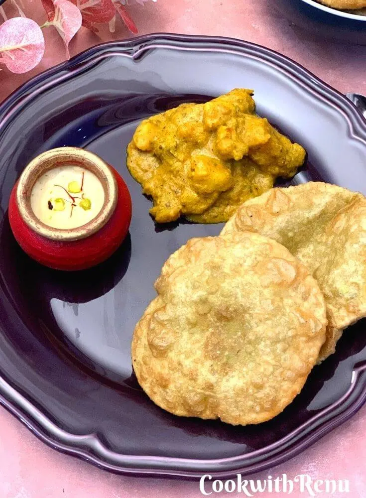 Close up look of Bengali Breakfast thali in a plate with Koraishutir Kochuri, Niramish Aloo Dum, and Mishti Doi.