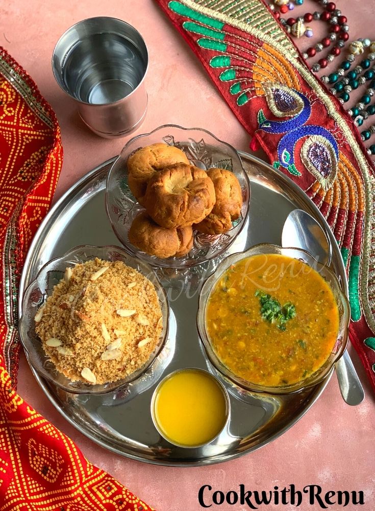 Rajasthani Dal Baati churma presented in a thali, along with some ghee (clarified butter) and water.