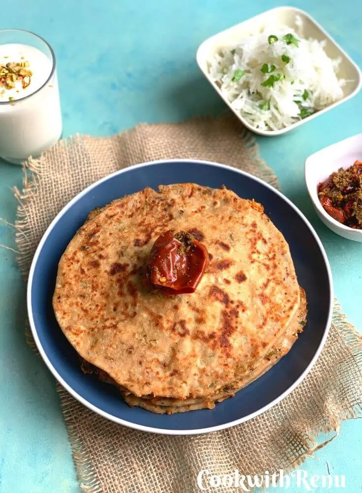 The Breakfast thali is served on a blue plate with Gobi paratha, mooli salad, pickle and yogurt lassi