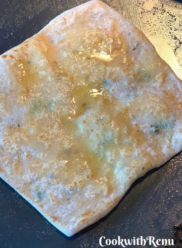 Applying ghee on the paratha on the top side
