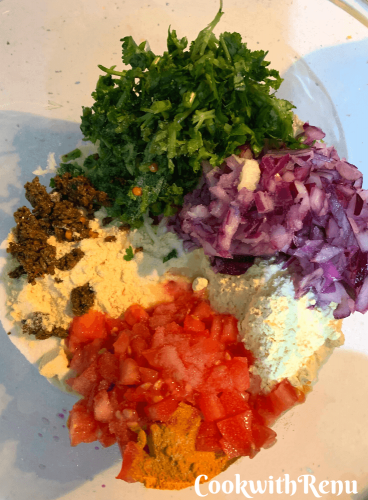 Adding of tomato, onion, pickle, coriander and spices in flour