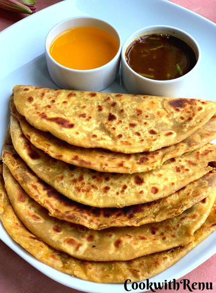 Three Puran Poli arranged on a white plate, served with ghee (Clarified butter) and katachi amti.