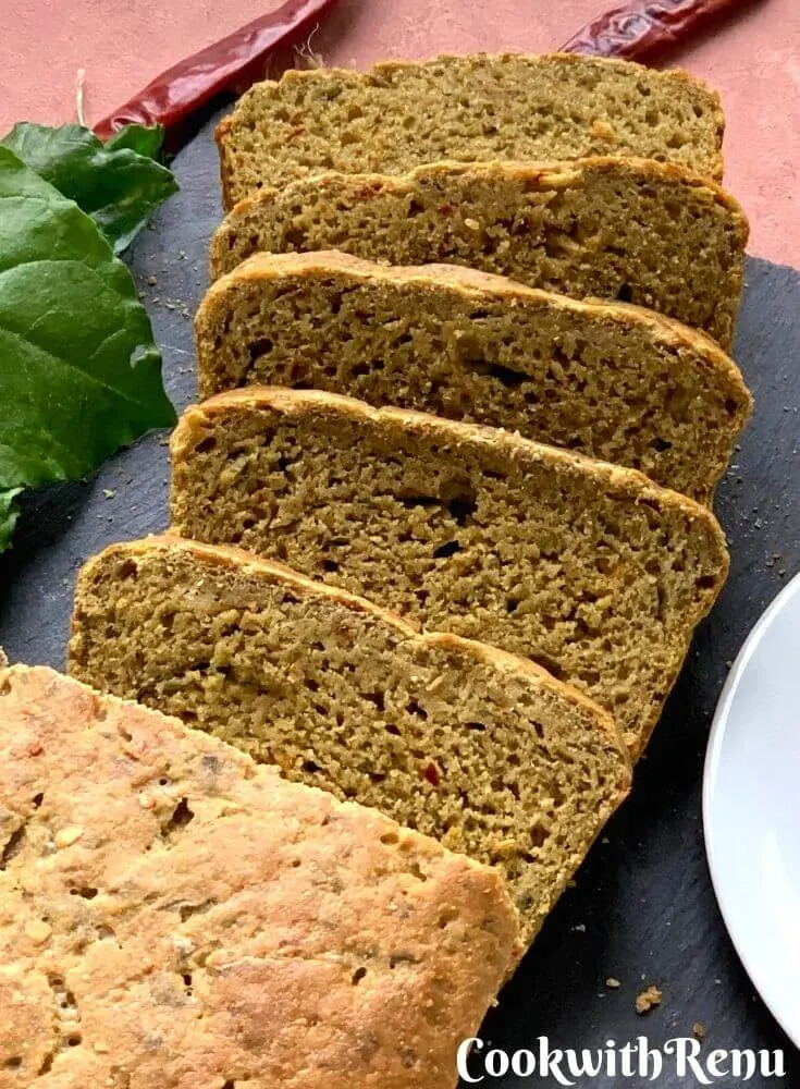 Close up look of the bread with slices cut. Texture of the bread can be seen closely with some spinach and red chilly flakes on the side