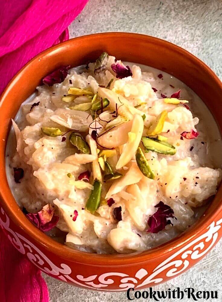 Close up look of Indian Rice pudding presented in designer brown bowl, garnished with almonds, pistachio, saffron and edible rose petals