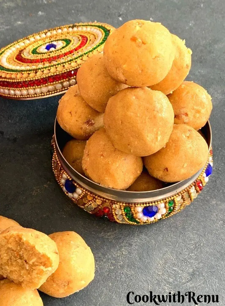 Close up look of ladoo served in a colorful box stacked one above the other in pyramid shape