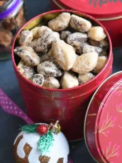 Spiced Brazil nuts in a gift tin with some Christmas Decorations seen on the side