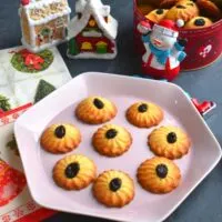 Spritz Cookies or Swedish Butter cookies are crispy, buttery cookies from the Scandinavia Cuisine and a must during Christmas. They are served on a pink plate with Snowman and Christmas decorations seen in background.