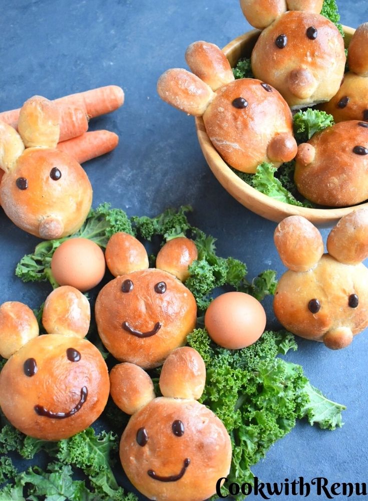 Bunny shaped buns laid on some green veggies along with eggs on the side. Also there are are more buns in the basket