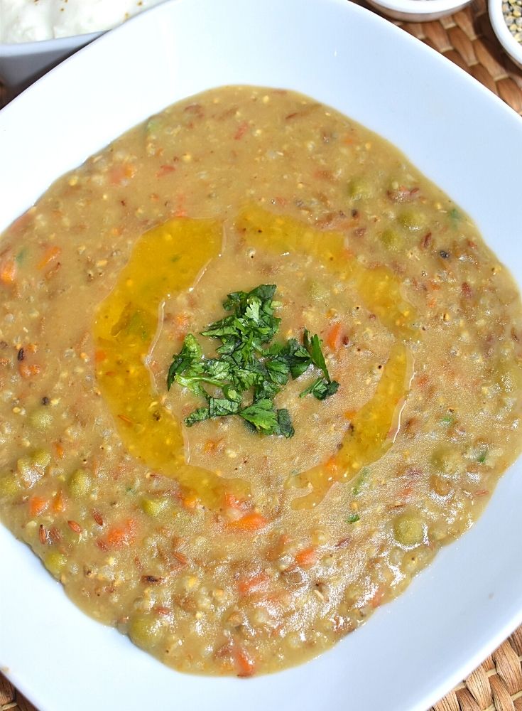 Bajra & Green Split Dal Khichdi served in a white bowl with ghee on top and garnished with coriander