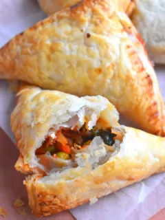 Close up look of cut puff pastry with filling seen inside. Seen in the background are few more puff lying.