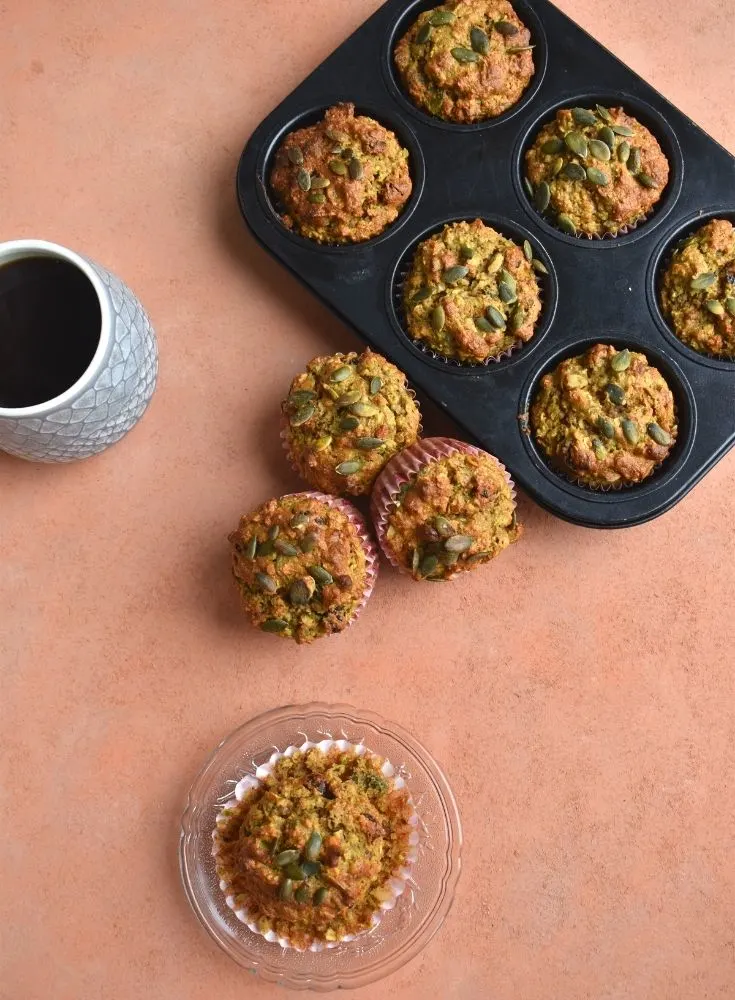 Top view of breakfast muffins on a plate and in muffin cases along with a cup of coffee