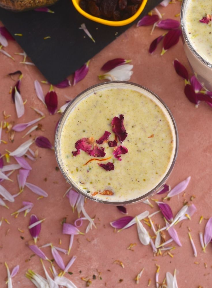 Close up look of A glass of Thandai with garnish of saffron and rose petals.