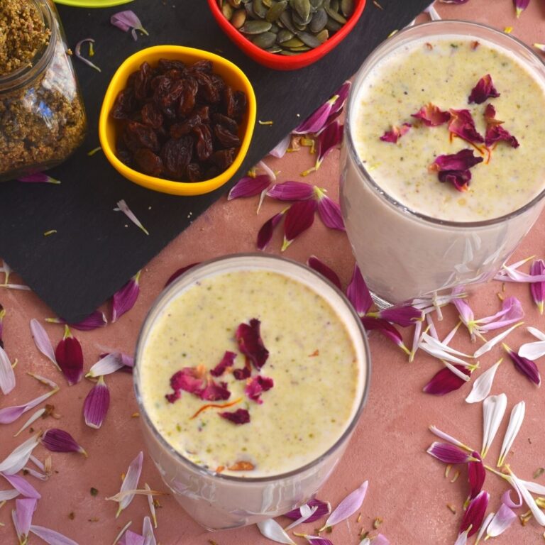 Close up look of A glass of Thandai with garnish of saffron and rose petals.