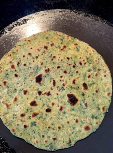 Paratha being half cooked on the bottom side, now ready to be cooked further
