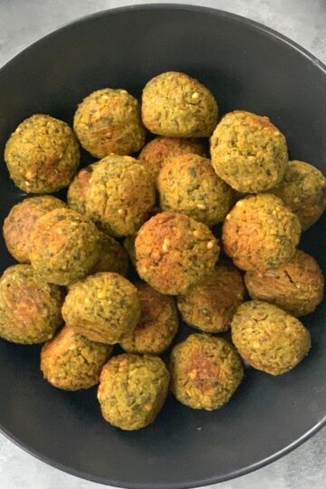Falafel seen on a black plate.