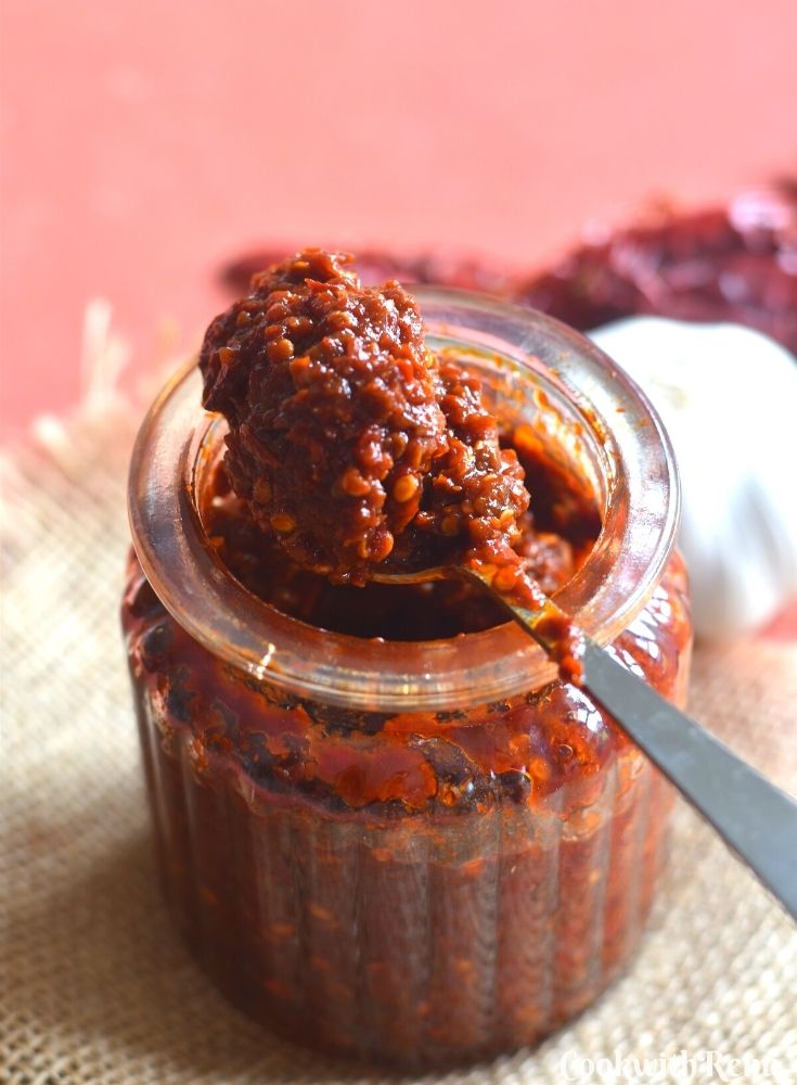 A glass jar filled with chutney and a spoon filled with chutney on top