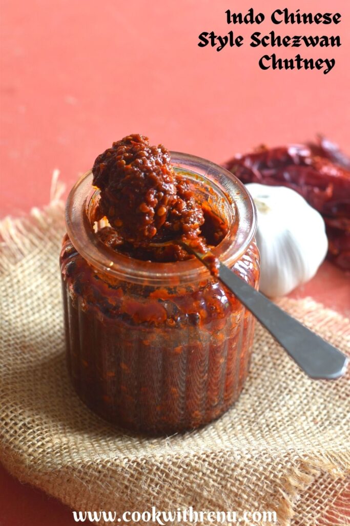 A glass jar filled with Indo Chinese Style Schezwan chutney and a spoon filled with chutney on top