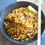 Vegan Pad Thai served in a black bowl with some lemon wedge served alongside