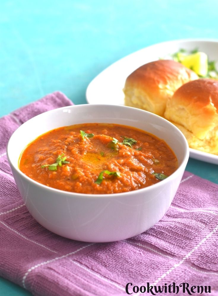 Pav Bhaji being served in a white bowl. Seen along side are some pav.