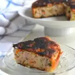 A slice of Savoury Luni Poda Pitha served on a plate. The soft and porus texture of the inside is clearly seen with crispy top and edges