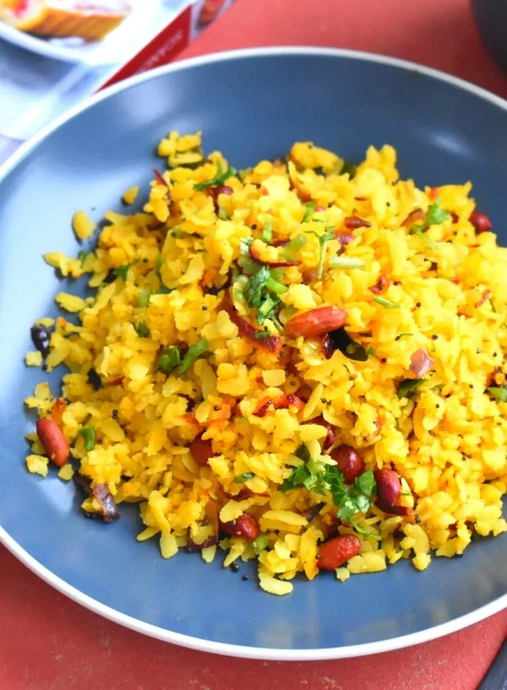 Kanda poha served in a blue plate. Seen in the background is a book