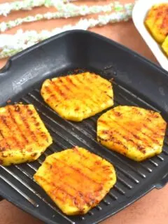 Peri Peri Grilled Pineapple on a grilled pan and seen in the background are more pineapple slices