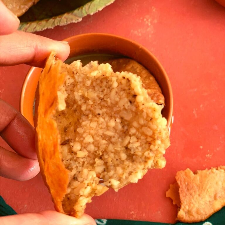 A close up look of an open piece of crispy bedai with stuffed urad dal. In the background are some more puris