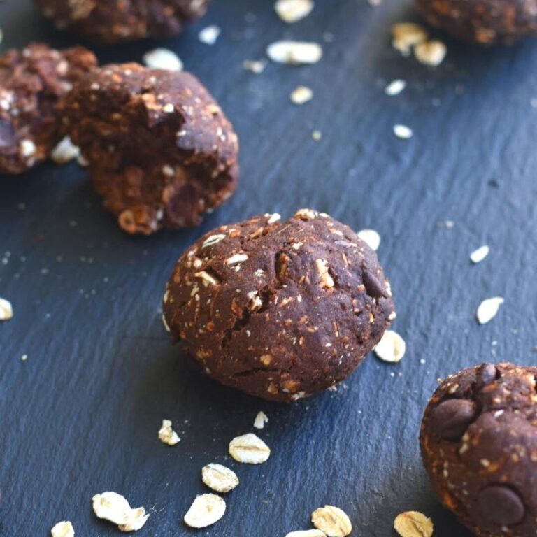 Oats and dates cookies served on a black cheese board with some oats lying