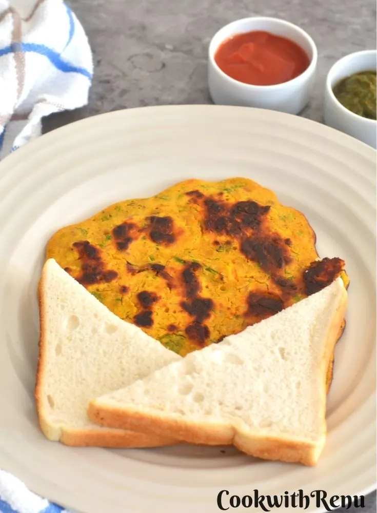 Vegan Chickpea Tomato Omeletee served with a bread slice along with tomato ketchup and green coriander chutney
