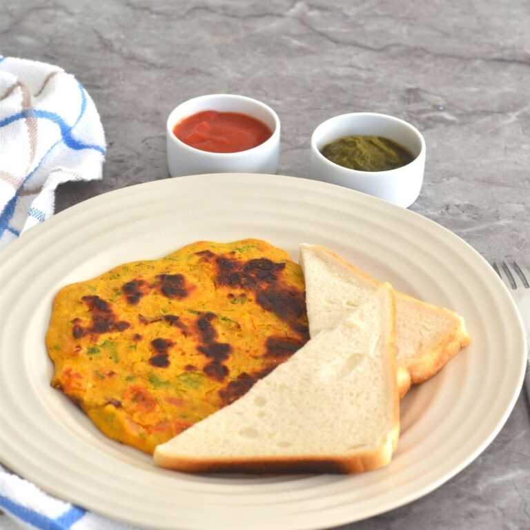 Vegan Chickpea Tomato Omeletee served with a bread slice along with tomato ketchup and green coriander chutney