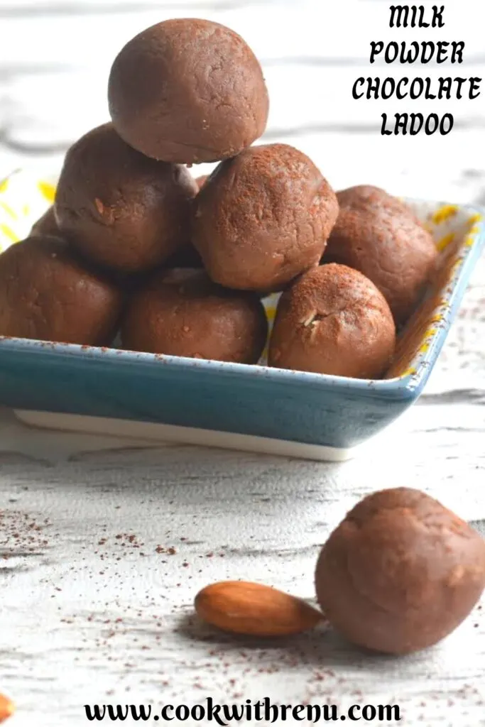A stack of Milk powder chocolate ladoo arranged on a rectangular plate with a garnish of cocoa powder. Seen along are some almonds scattered.