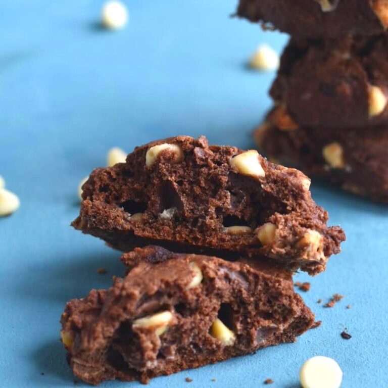 Close up texture of chocolate chip cookies and a stack of chocolate chip cookies seen behind with white chocolate on the board