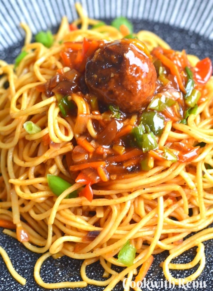 Vegetarian Hakka Noodles served with Vegetarian Manchurian on a black plate