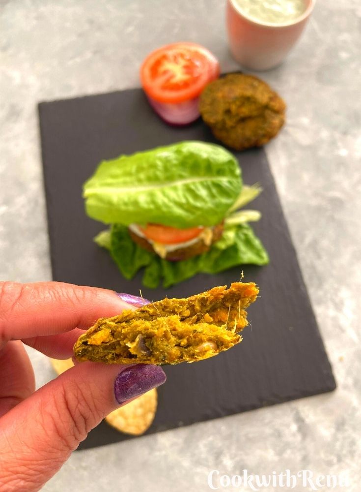 A close up look of vegan chickpea patties inside texture. Seen in the background is the chickpea served on lettuce wraps along with tomato, onion and nasturtium dip